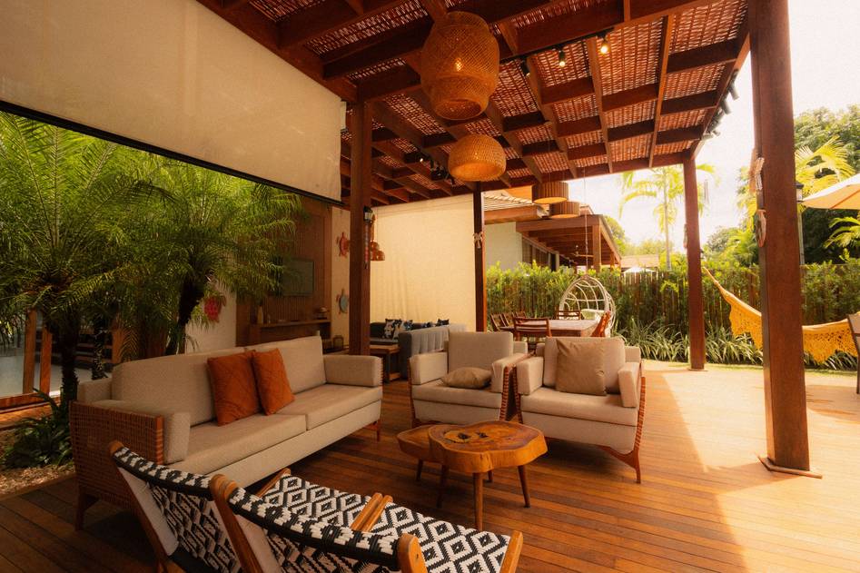 Elegant wooden pergola with matching outdoor furniture set featuring neutral cushions, string lights, and potted greenery